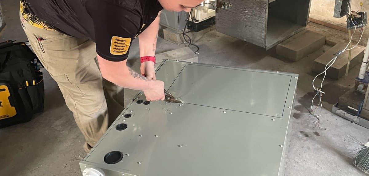 Trust 1 technician preparing a new furnace for installation in a basement