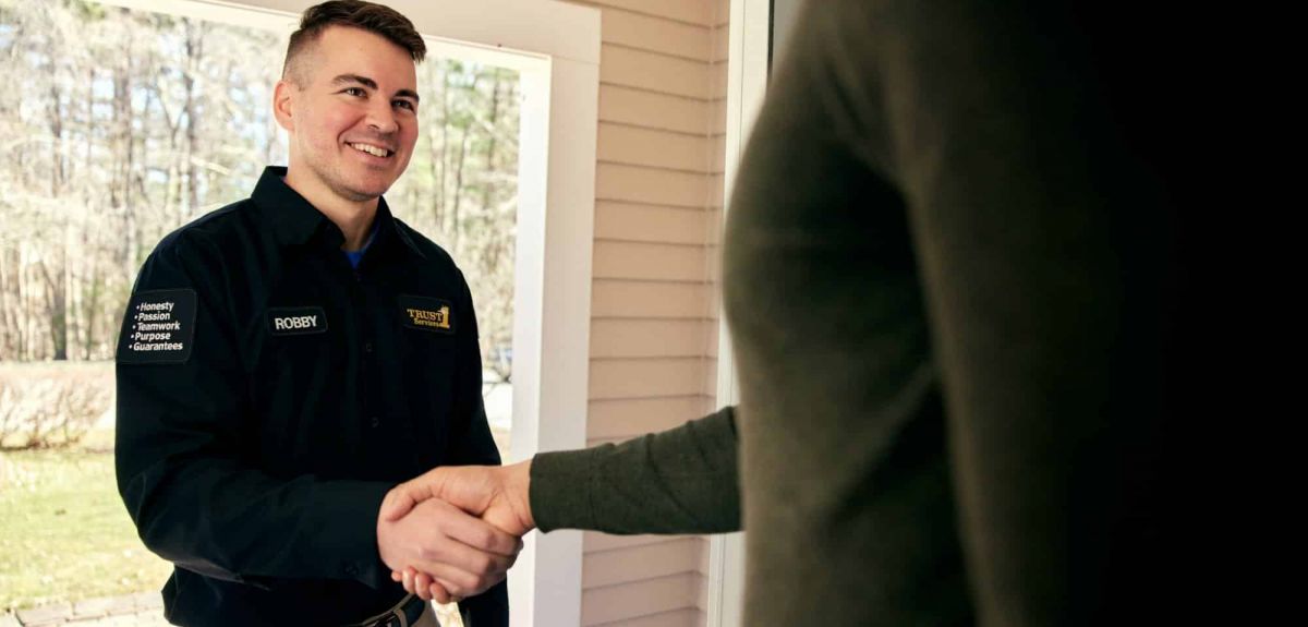 Trust 1 technician shaking hands with a homeowner at the front door