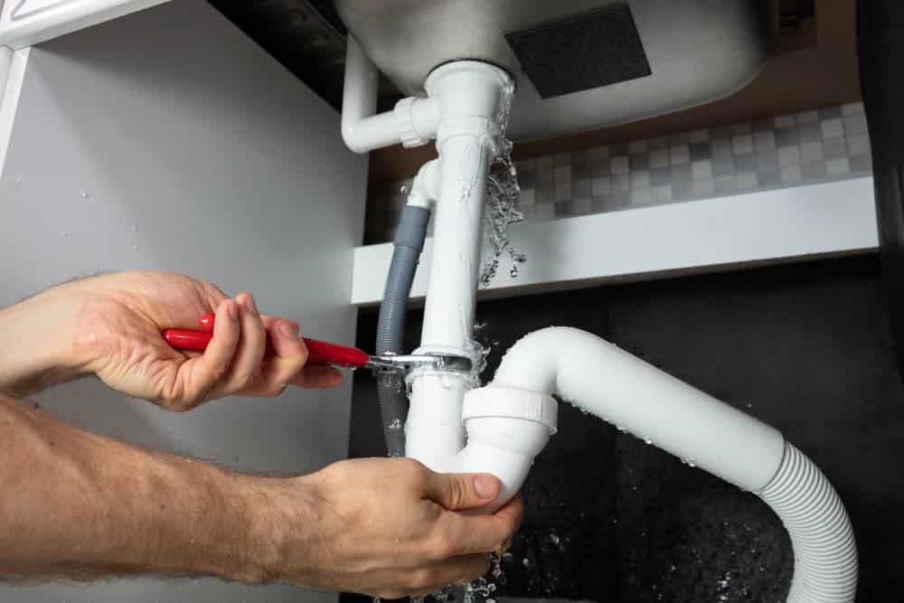 Plumber Fixing White Sink Pipe With Adjustable Wrench