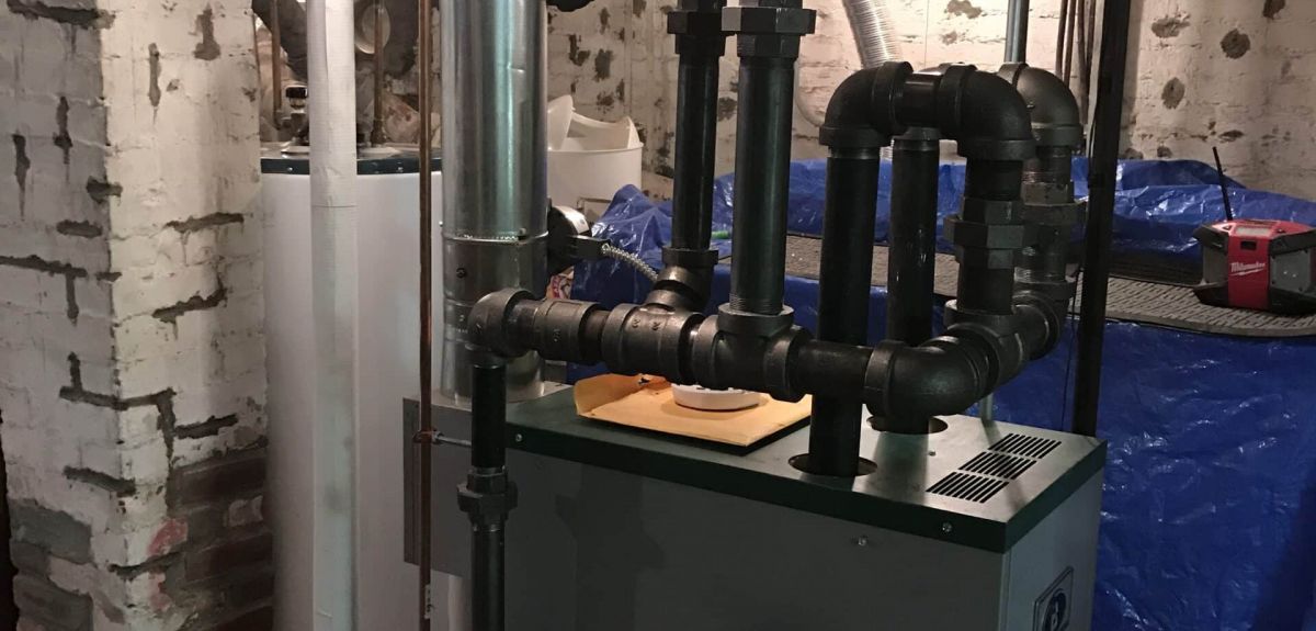 New gas steam boiler with black iron near-boiler piping installed by Trust 1 in a Greater Boston basement