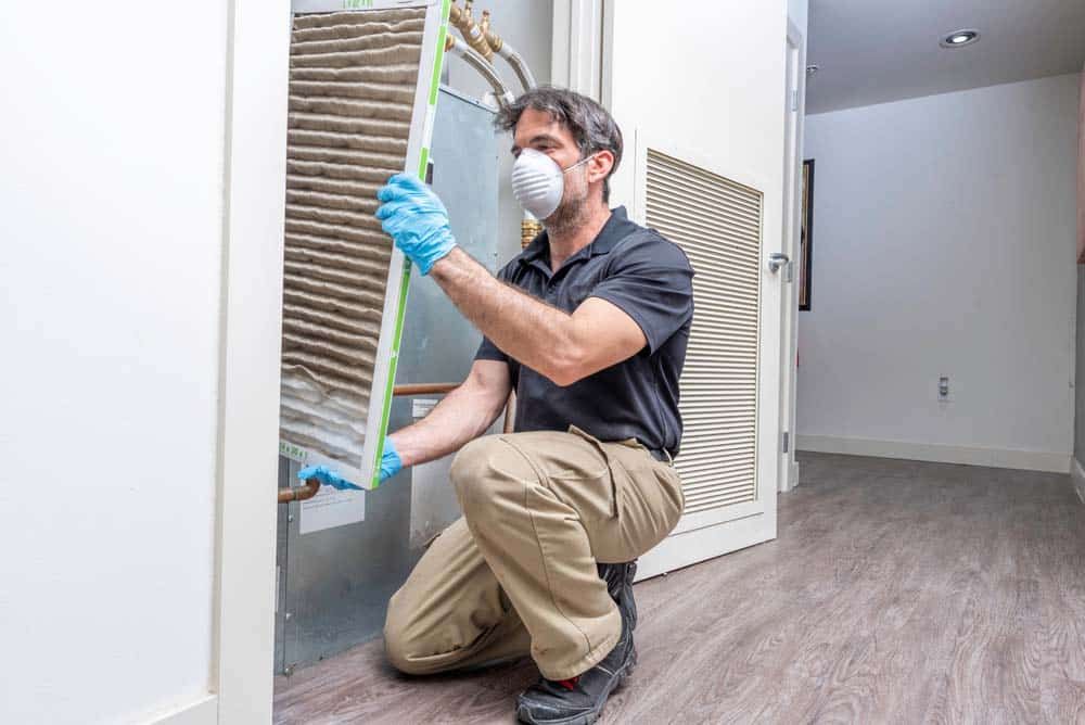 Hvac technician removing a dirty air filter from a heat pump