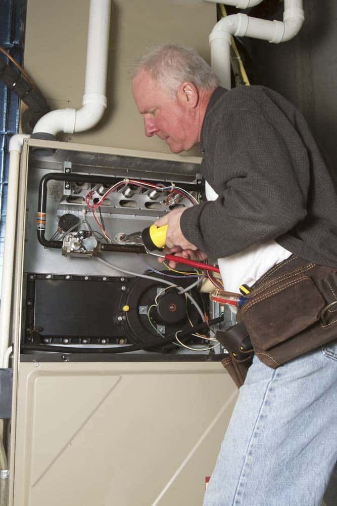 technician repairing basement furnace unit