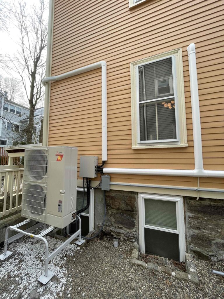 Mitsubishi multi-zone heat pump outdoor unit installed by Trust 1 on a raised stand with line set covers